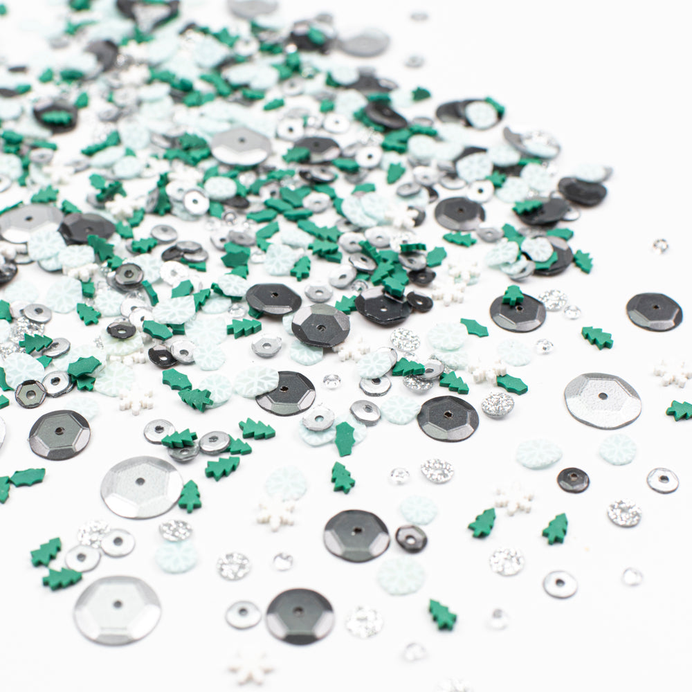 Assorted sequins and embellishments in green, silver, and white on a white background