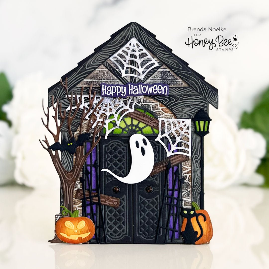 Handmade Halloween card featuring a spooky house with a ghost, pumpkin, and spiderwebs.