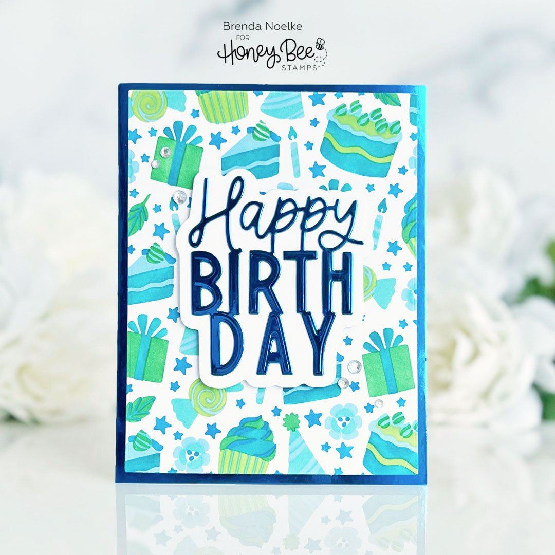 Handmade birthday card with blue and green stenciled cakes and 'Happy Birthday' die-cut text.