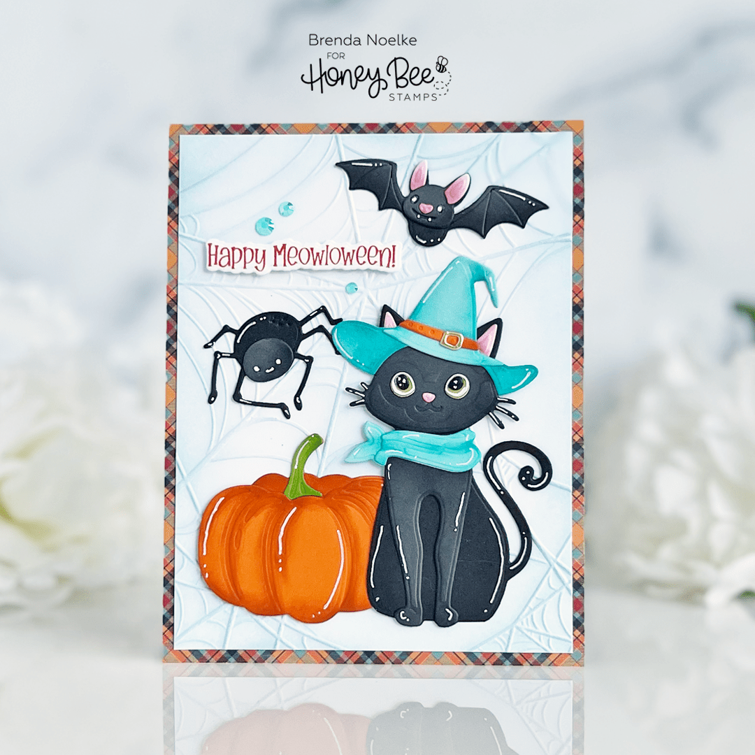 Handmade Halloween card featuring a black cat in a witch hat, a pumpkin, a spider, and a bat.