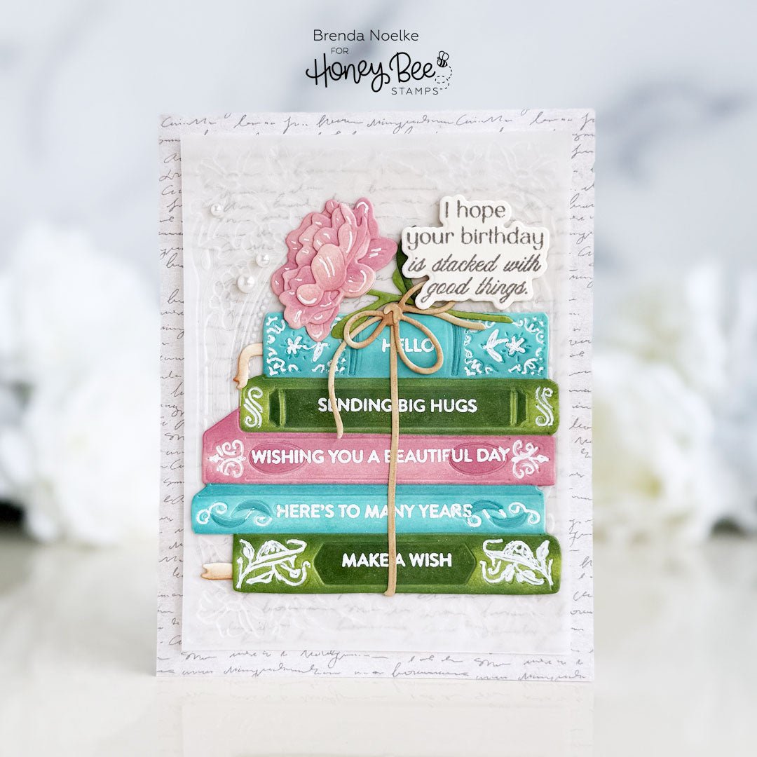 Handmade birthday card featuring a colorful stack of books, a pink flower, and birthday sentiments.