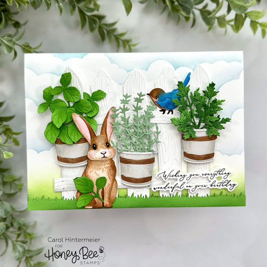 Handmade birthday card featuring a layered garden scene with a bunny, bluebird, and potted herbs.