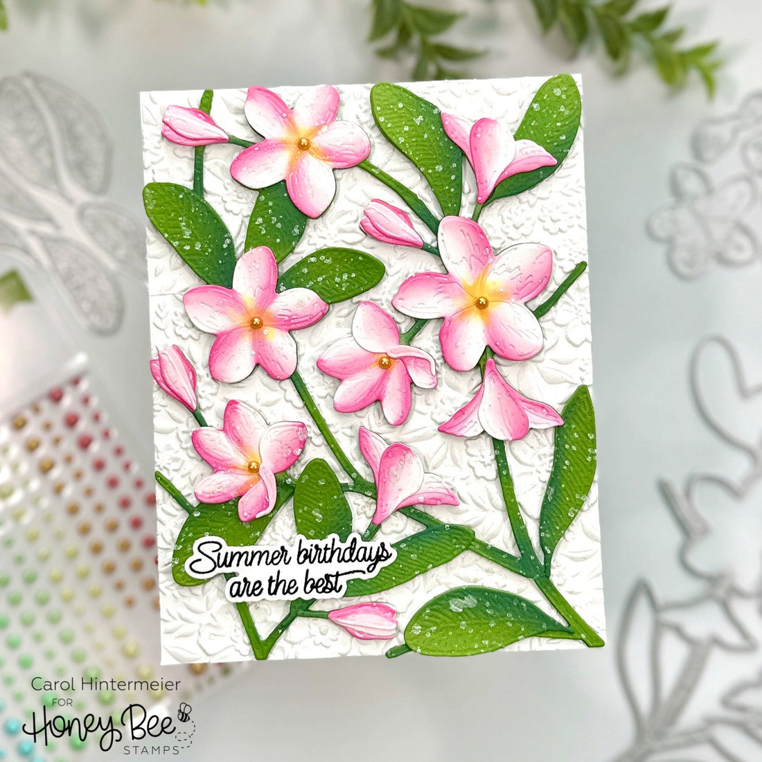 Handmade card with 3D pink plumeria flowers and green leaves reading Summer birthdays are the best