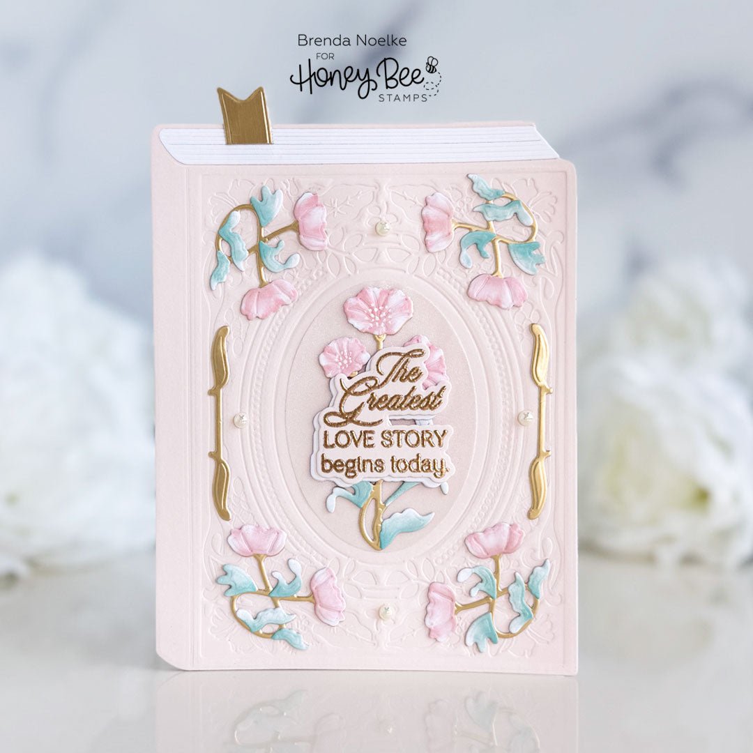 Handmade pink card shaped like a book with floral accents and 'The Greatest Love Story' text.