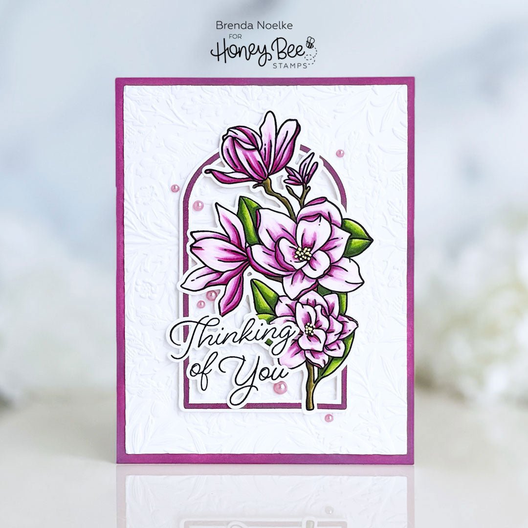 Handmade 'Thinking of You' card with pink magnolia flower stamps and embossed white background.