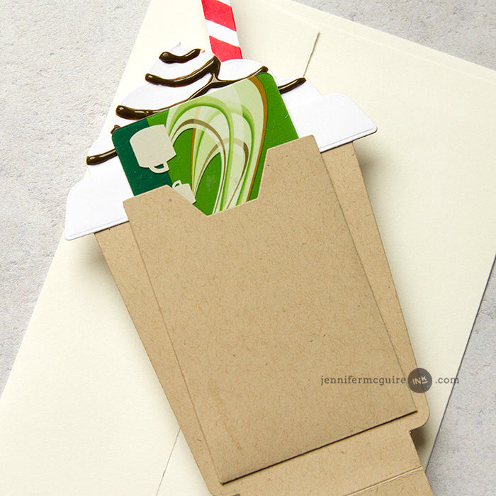 Kraft paper envelope with a candy cane and green card on a gray background