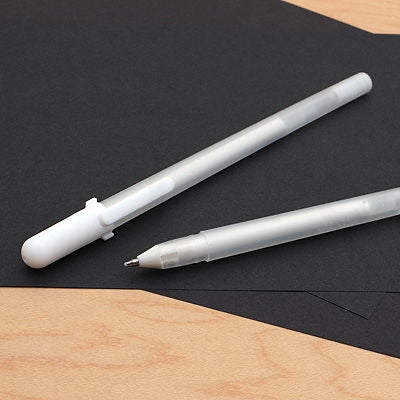 Two white pens on black paper