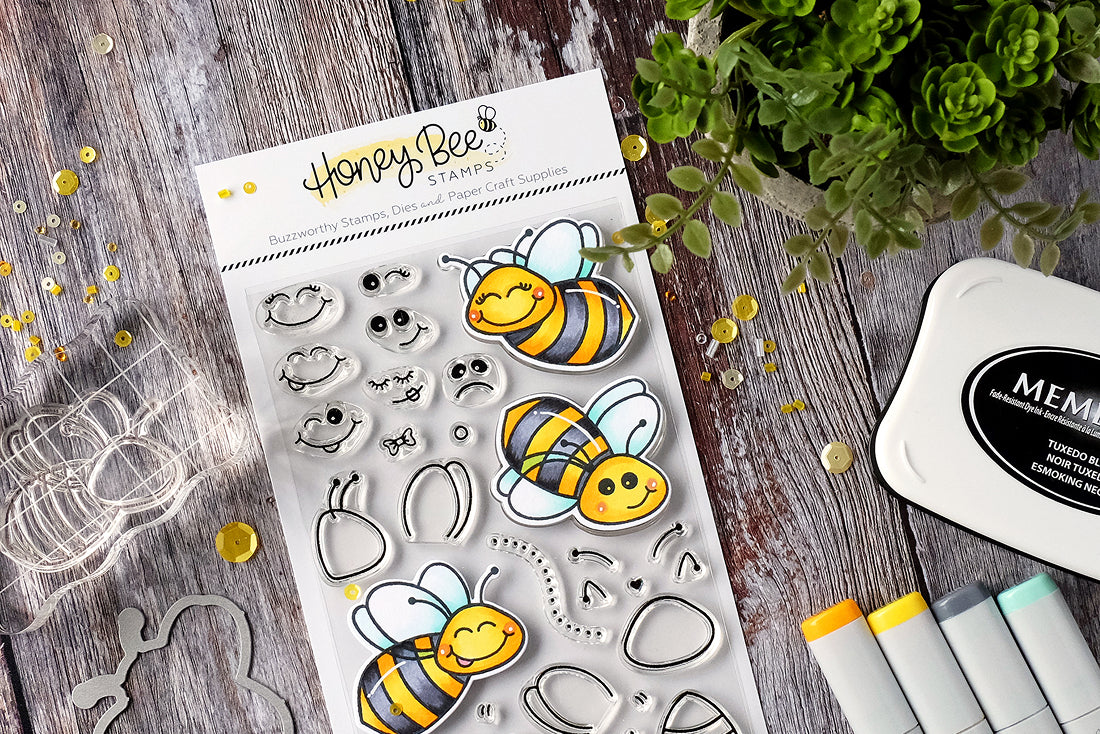 Honey Bee clear stamps with bumblebee designs on a wooden surface with ink pads and tools.