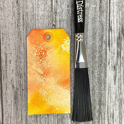 Distress brush and watercolor tag on a wooden surface