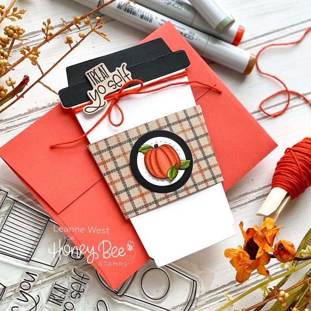 Autumn-themed card with plaid design and pumpkin illustration, surrounded by craft supplies on a wooden surface.
