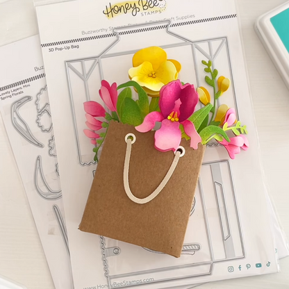Card with 3D pop-up flowers and a paper bag, featuring Honey Bee Stamps branding.