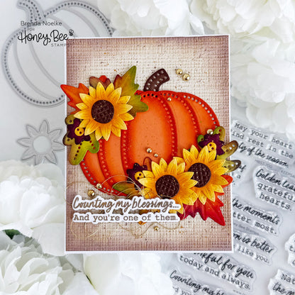 A handmade autumn-themed greeting card featuring a layered orange pumpkin, yellow sunflowers, and fall leaves on a burlap-textured background, with the phrase 'Counting my blessings.