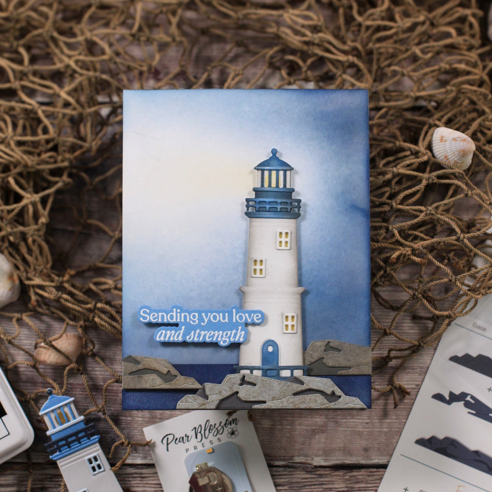 Card with a lighthouse design and text 'Sending you love and strength' on a textured surface.