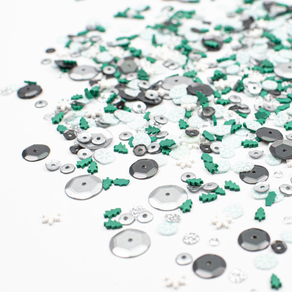 Assorted sequins in silver, green, and white on a white background