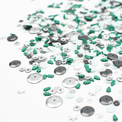 Assorted sequins in silver, green, and white on a white background