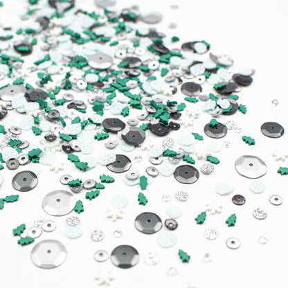 Assorted sequins and embellishments in green, silver, and white on a white background