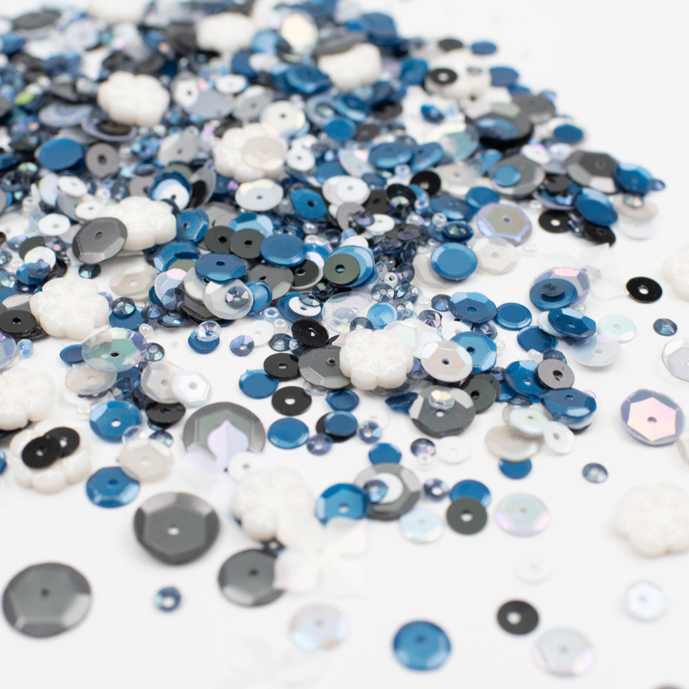 Assorted blue, black, and white sequins on a white background