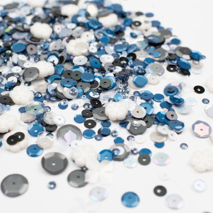 Assorted blue, black, and white sequins on a white background