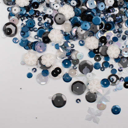 Assorted blue, black, and white sequins on a light gray background