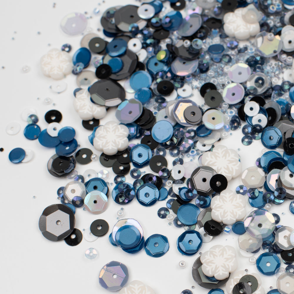 Assorted blue, black, and white sequins on a white background