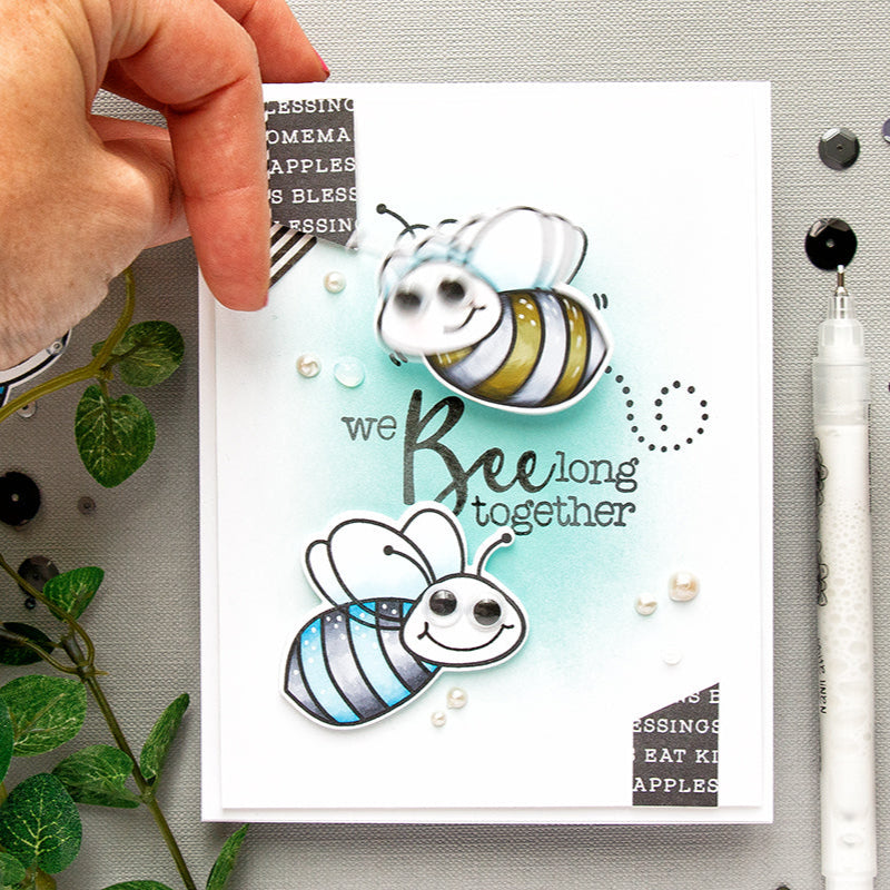 Handmade card with bee illustrations and text 'we Bee long together' on a gray surface.